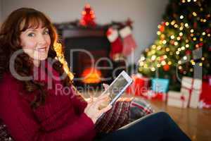 Smiling redhead using tablet at christmas