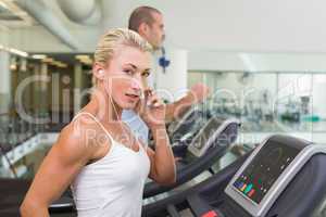 Fit couple running on treadmills at gym