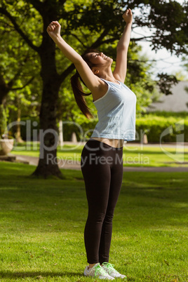 Side view of healthy woman stretching hands in park