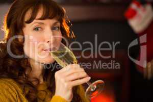 Pretty redhead drinking glass of champagne on couch