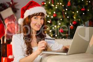 Smiling redhead shopping online with laptop