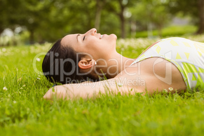 Peaceful fit brunette lying on the grass