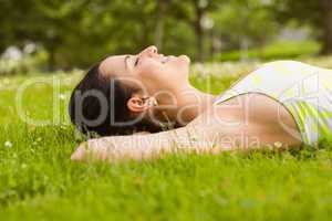 Peaceful fit brunette lying on the grass