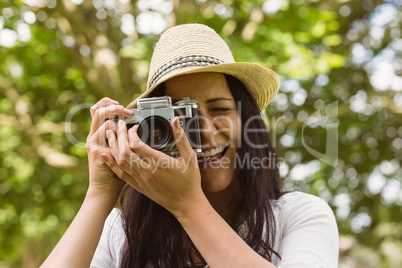 Smiling brunette in straw hat taking picture
