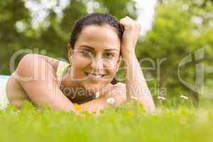 Cheerful fit brunette lying on the grass