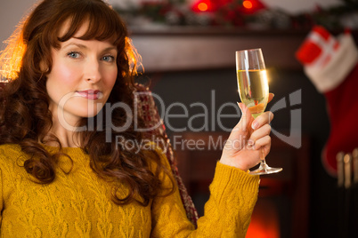 Redhead holding glass of champagne on couch at christmas