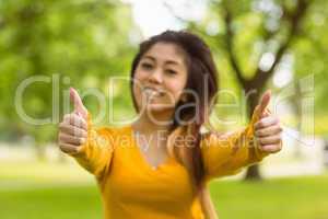 Beautiful woman gesturing thumbs up in park