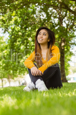 Beautiful relaxed woman sitting on grass at park