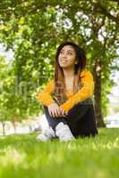 Beautiful relaxed woman sitting on grass at park