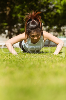 Healthy woman doing push ups in park