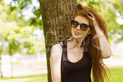 Beautiful young woman against tree in park