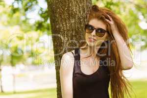 Beautiful young woman against tree in park