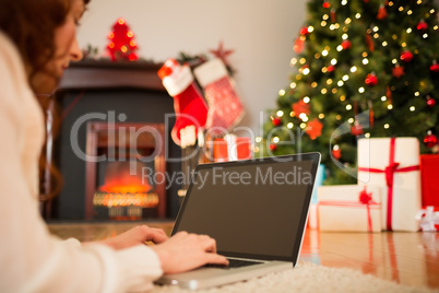 Redhead woman lying on floor using laptop at christmas