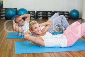 Fit couple doing abdominal crunches at the gym