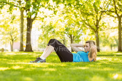 Fit blonde doing sit ups in the park