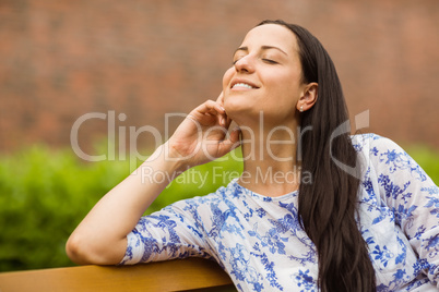 Smiling brunette sitting on bench relaxing Smiling brunette sitting on bench relaxing