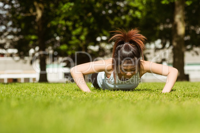 Healthy woman doing push ups in park