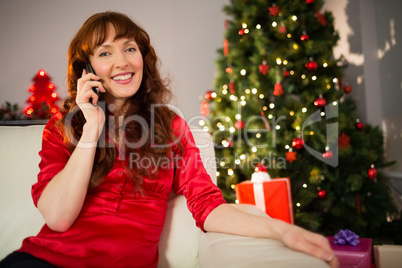 Pretty redhead sitting on the couch phoning