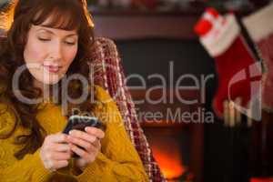 Cheerful redhead using mobile at christmas