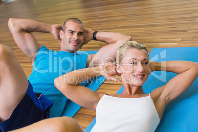 Sporty couple doing abdominal crunches at fitness studio