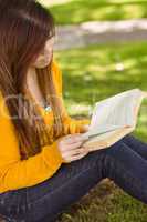 Relaxed female student reading book in park