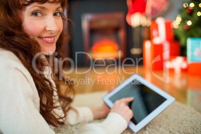 Redhead woman lying on floor using tablet at christmas