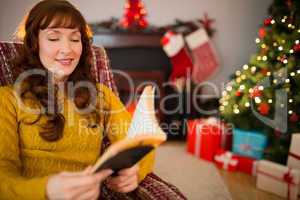 Cheerful red hair reading a book at christmas