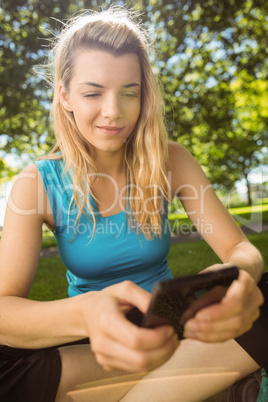 Fit blonde texting on her smartphone