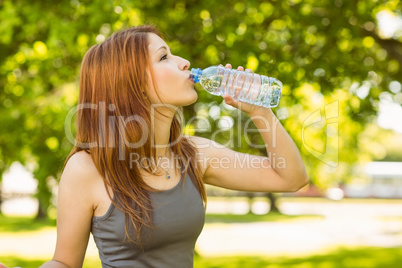 Pretty redhead drinking water in park