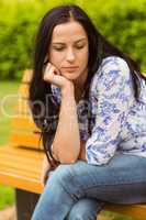 Thoughtful casual brunette sitting on bench