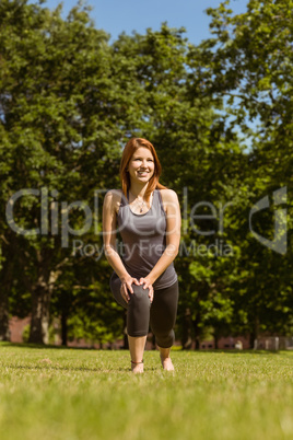 Pretty athletic redhead stretching in park