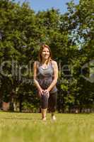 Pretty athletic redhead stretching in park