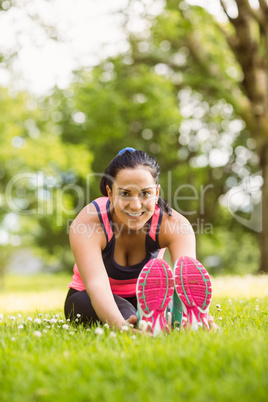 Athletic brunette stretching on the grass