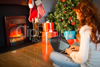 Redhead woman sitting on floor using laptop at christmas