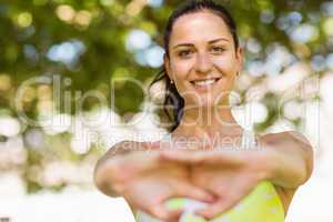 Happy fit brunette stretching in the park