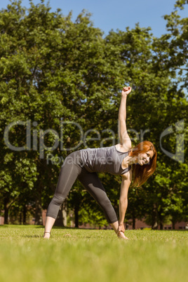 Pretty athletic redhead stretching in park