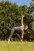 Pretty athletic redhead stretching in park