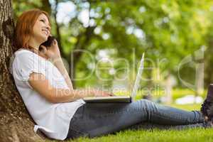 Pretty redhead on the phone holding her laptop