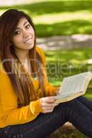 Relaxed female student reading book in park