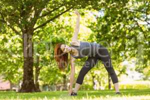 Pretty athletic redhead stretching in park