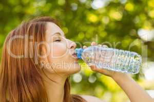Pretty redhead drinking water in park