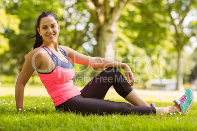 Smiling fit brunette relaxing on the grass