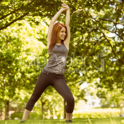 Pretty athletic redhead stretching in park