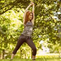 Pretty athletic redhead stretching in park