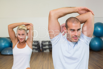 Couple stretching hands behind back in yoga class