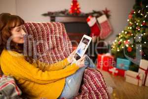 Redhead woman sitting on couch using tablet at christmas