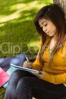 Female college student doing homework in park