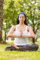 Fit brunette sitting in lotus pose with hands together