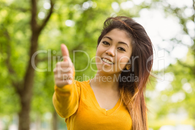 Beautiful woman gesturing thumbs up in park