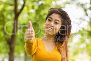 Beautiful woman gesturing thumbs up in park